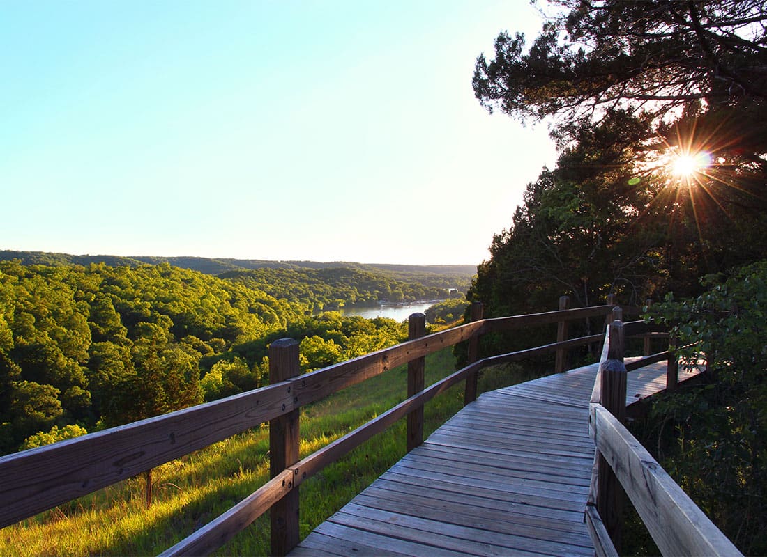 Service Center - Scenic View of a Wooden Bridge in a State Park at Sunset with Views of Green Trees and Moutains in the Distance